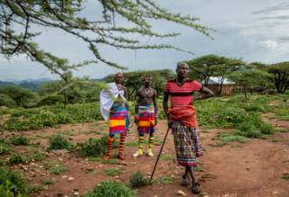 Zwei Samburu-Krieger sprechen mit Tiampati Leletit, der 80 seiner Ziegen verlor, als die Heuschrecken eintrafen