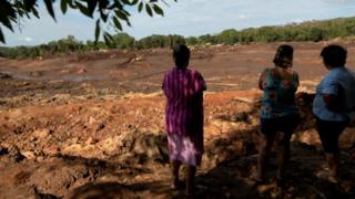 Moradores olham para área destruída pela lama, em Brumadinho