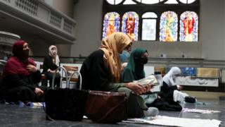 Frauen mit Kopftuch und Gesichtsmaske besuchen die Freitagsgebete in einer Berliner Kirche