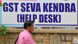 A pedestrian walks past a poster advertising about the new goods and services tax (GST) regime at the Service Tax Office in Bangalore on June 29, 2017