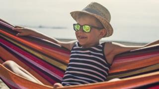 Young boy wearing sunglasses and a hat - chilling out on a hammock
