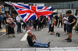 A woman waves a British Union Jack flag during a protest near the government headquarters in Hong Kong on June 21, 2019