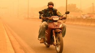 in_pictures A man rides his motorcycle during a sandstorm