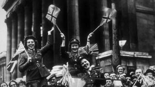 Члены Вспомогательной территориальной службы (ATS) проезжают по Трафальгарской площади в служебном автомобиле во время празднования Дня Победы в Лондоне, 8 мая 1945 года.