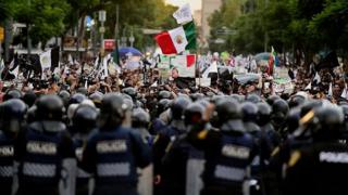 Protesters face a line of riot police in Mexico City