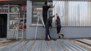 Men cover the windows of a car parts store in preparation for Hurricane Irma in San Juan
