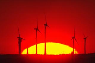 The sun rises behind wind turbines near the Pankow motorway junction, Berlin