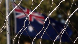 An Australian flag behind a wire fence