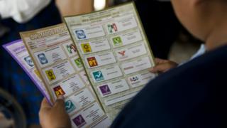 Mujer con cédulas de votación