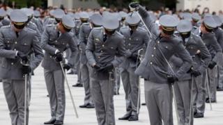 Cadetes enfileirados e fardados empunham espada