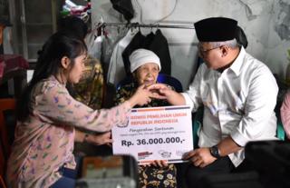 Ketua KPU Arief Budiman (kanan) menyerahkan santunan kepada keluarga almarhum Tutung Suryadi, petugas KPPS yang meninggal.