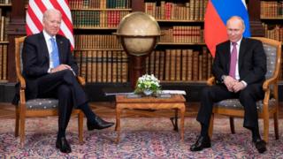 president joe biden and president vladimir putin sitting apart from one another in geneva in 2021 looking uncomfortable