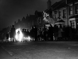 People gather around a bonfire in the street