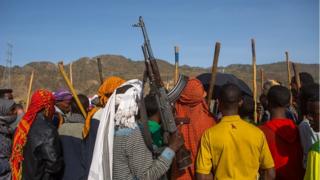 ሰዎች የጦርመሣሪያ እና ዱላ ይዘው ሲጨፍሩ