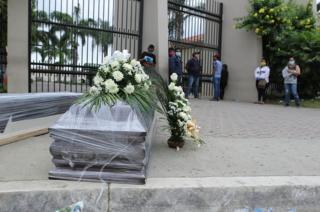 Relatives of a dead person line up for a funeral outside the Durán cemetery