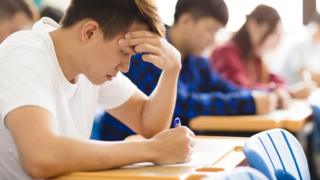 Jovem estudando com colegas em segundo plano