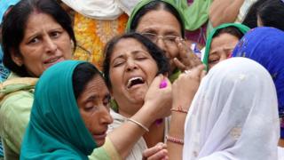 Indian relatives of bus accident victims cry as the bodies (not pictured) are carried to a funeral