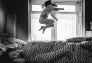 A child jumps on the bed.