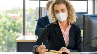 Woman wearing mask working in an office