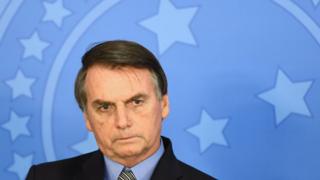 Bolsonaro aparece compenetrado em frente a painel em evento em Brasília