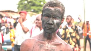 A man with a face painted with charcoal in a street of Arondizuogu during the Ikeji Festival in Nigeria