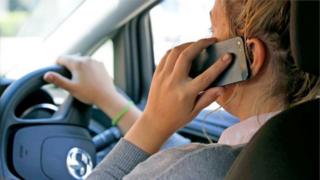 Женщина-водитель держит мобильный телефон у уха