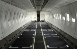 Eine Innenansicht eines leeren Flugzeugs, dem die Sitze entzogen wurden.