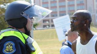 Un funcionario policial observa a un hombre que protesta contra el veredicto de no culpabilidad de un policía que mat'o a un menor en St. Louis, Missouri.
