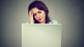 Mujer mirando computadora con cara de preocupada.