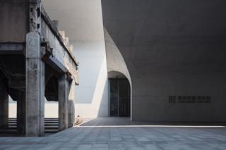 A man sitting on the ground surrounded by concrete architecture