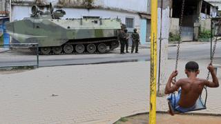 Garoto num balanço observa tanque da Marinha no Rio de Janeiro
