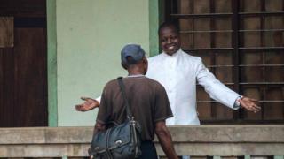 Father Lucien Ambunga, a Catholic priest who survived the Ebola virus, welcomes a faithful at the St Joseph Church in Itipo on June 11, 2018.