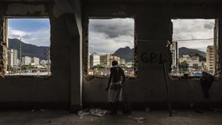 A man stands at the windows of the abandoned Ministry of Finance building (now an occupied building/squat) in the 'Favela' Mangueira community, North Zone, Rio de Janeiro, Brazil
