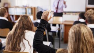 Девушка поднимает руку, чтобы задать вопрос в школе