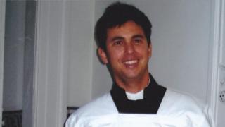 Guido sorri em foto, onde aparece de traje católico