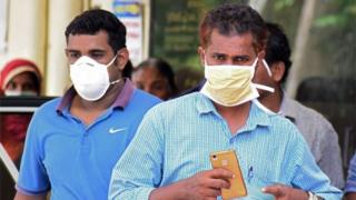 Indian residents wear face mask outside the Medical College hospital in Kozhikode on May 21, 2018