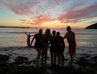 Swimmers on a beach at sunrise