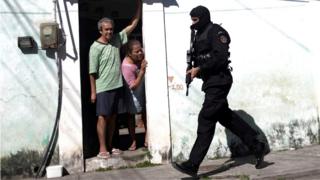 Residentes da Cidade de Deus olham para policial