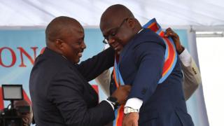 Prezida avuyeko Joseph Kabila (i bubamfu) yambika umutamana umukuru w'igihugu mushasha wa Republika ya Demokrasi ya Kongo, Felix Tshisekedi (i buryo)