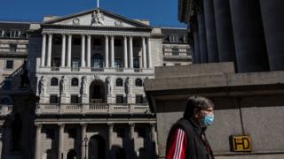 A masked man walks past the Bank of England in London