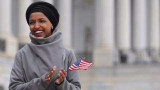 Ilhan Omar poses with an American Flag outside of the US Capitol