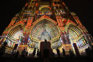 People gather outside Amiens Cathedral in France, which is lit up at night