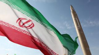 Iranian flag flying at an undisclosed location in Iran next to a surface-to-surface Qiam-1 missile (20 August 2010)