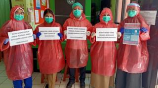 Indonesian nurses wear raincoats to protect themselves from virus