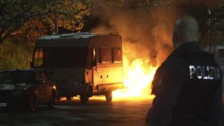 Изображение показывает автомобиль в огне во время акции протеста