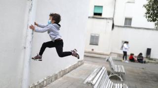 Kilian, 6, wears a protective face mask as he jumps from a bench, after restrictions were partially lifted for children, during the coronavirus disease (COVID-19) outbreak, in Igualada, Spain, on 26 April 2020