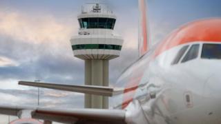 Stock image of an airport control tower with a plane in the foreground