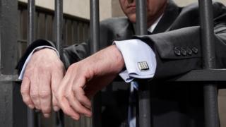 Man in suit behind bars