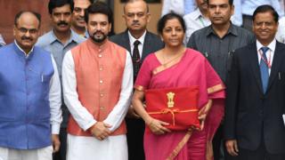 Indian Finance Minister Nirmala Sitharaman (2R) with Minister of State for Finance Anurag Thakur (2L) looks on as she poses for a picture with her staff before leaving the Indian Finance Ministry for Parliament House to table the General Budget 2019-20 in New Delhi on July 5, 2019.