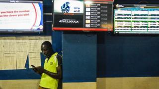 Umugabo wo mu murwa mukuru Kampala apima amahirwe ye mu mikino y'umupira w'amaguru y'i Burayi, akoresheje telefoni ye igendanwa